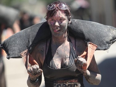 Jessica Larson with a mud splattered grin hauls a sand bag during the Pack Mule section of the  Rugged Maniac run Saturday July 17, 2015 at Rocky Mountain Show Jumping. Hundreds of adventurers ran, climbed and slogging through a 5 kilometre course of ropes, towers, mud and fire. The show travels across North America with it's next Canadian stop in Vancouver August 15.