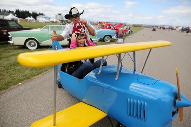 Miss Rodeo Airdrie Kelsey Reinboldt-Lynch switches hats with Shriner Ron Down during the Wings Over Springbank air show at Springbank Airport west of Calgary on July 19, 2015.