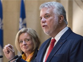 Quebec Premier Philippe Couillard responds to reporters' questions as Alberta Premier Rachel Notley looks on, at a joint news conference in Quebec City on July 14.