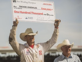 Trevor Knowles, centre, wins the $100,000 prize for the steer wrestling Championship at the Calgary Stampede rodeo on Sunday. It's the fourth time he's held that oversized cheque above his head.