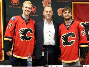 New Calgary Flames players Dougie Hamilton, left and Michael Frolik, right join Brad Treliving, general manager of the flames, during a press conference at the Scotiabank Saddledome on July 17, 2015.