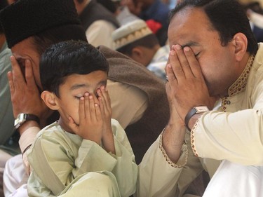 Osman Ahmad and his four year old son Hussan pray during the Eid ceremony, marking the end of the holy month of Ramadan, Saturday July 18, 2015 at Baitun Nur Mosque mosque. Muslims attend the congregational Eid prayer service the morning after the end of Ramadan.