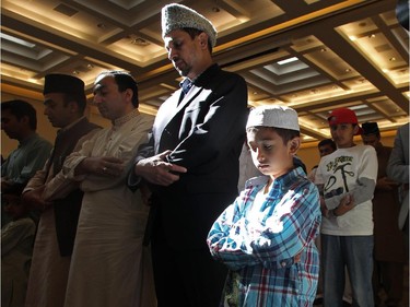 Muzaffar Sultan and his son Sherg, age 13, pray during the Eid ceremony, marking the end of the holy month of Ramadan, Saturday July 18, 2015 at Baitun Nur Mosque mosque. Muslims attend the congregational Eid prayer service the morning after the end of Ramadan.