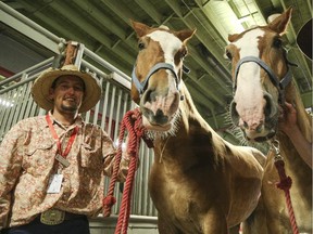James Gaudry stands with John and Wayne, two horses used in the heavy horse pull event, at the Stampede Barns.