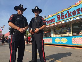 Sgt. Tat Ng, left, and Sgt. Chris Terry pose for a photo on the Calgary Stampede grounds on Wednesday, July 8 during their patrol.