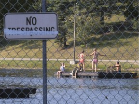 People continue to swim in Lake Bonavista despite the swimmer's itch warning sign posted at the private lake's entrance in Calgary, on July 9, 2015.