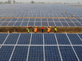 Workers install panels in a big solar power project in India.