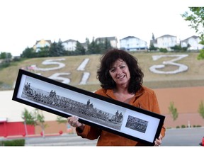 Local artist Phyllis Wheaton holds a historic picture commemorating the white stones of Signal Hill. The site is nearing its 100th anniversary in December 2015.