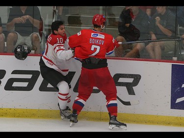 Team Canada player Nick Merkley, left, has his helmet knocked off during a check against Team Russia player Sergey Boikov in the opening game of the World's Junior Showcase at the Markin MacPhail Centre in Calgary on Monday, Aug. 3, 2015. Team Canada led over Team Russia, 3-1, at the end of the second period.
