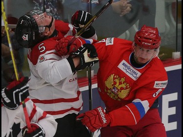 Team Canada player Travis Dermott, left, has his head pushed into the glass by Team Russia player Denis Guryanov in the opening game of the World's Junior Showcase at the Markin MacPhail Centre in Calgary on Monday, Aug. 3, 2015. Team Canada led over Team Russia, 3-1, at the end of the second period.