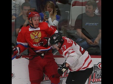 Team Russia player Egor Rykov, left, is pushed into the boards by Team Canada player Mitchell Stephens in the opening game of the World's Junior Showcase at the Markin MacPhail Centre in Calgary on Monday, Aug. 3, 2015. Team Canada won over Team Russia, 4-1.