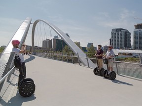 Peter Kominek, left, stops to take photos for Dan and Adam Coates during a Segway tour of the East Village and St. Patrick's Island in Calgary on Monday, Aug. 10, 2015.