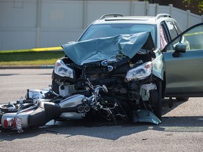 A motorcycle lies underneath a Subaru SUV in a fatal crash along Old Coach Banff Road in Calgary on Wednesday, Aug. 12, 2015.