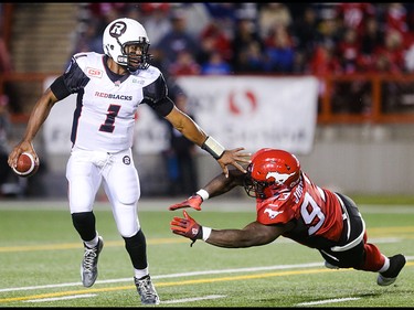 Ottawa Redblacks quarterback Henry Burris, left, avoids being sacked for a second time in a row by Calgary Stampeder defensive lineman Micah Johnson at McMahon Stadium in Calgary on Saturday, Aug. 15, 2015. The Calgary Stampeders led the Ottawa Redblacks, 31-3, at the half in regular season CFL play.