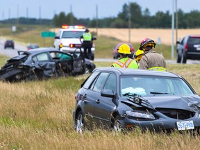 Two vehicles involved in a multiple vehicle collision are inspected by firefighters and the RCMP along Highway 1A and Lochend Road outside of Calgary on Thursday, Aug. 20, 2015.