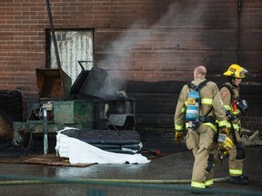Firefighters inspect the remains of a fire at Bishop McNally High School in Calgary on Tuesday, Aug. 18, 2015.