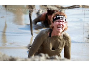 Carmen White crawls under some barbwire in the mud while taking part in the Spartan Race. a 5Km obstacle course, in Calgary over the weekend.