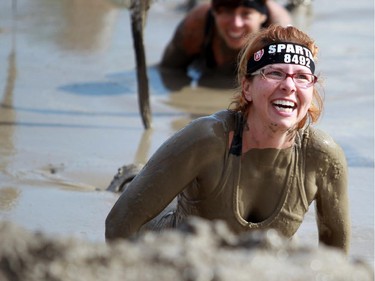 Carmen White crawls under some barbwire in the mud while taking part in the Spartan Race. a 5Km obstacle course, in Calgary over the weekend.