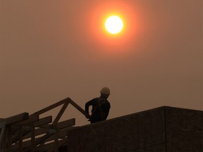 A construction worker in Bridgeland is silhouetted by the smoke-shrouded sun at about 8:30 on Tuesday morning. The city is forecasted to be under heavy smoke warnings for at least another day.