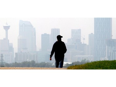 Charlie Coffin walks along the pathway above Max Bell Centre with the smoke shrouded downtown in the distance in Calgary Monday August 24, 2015.