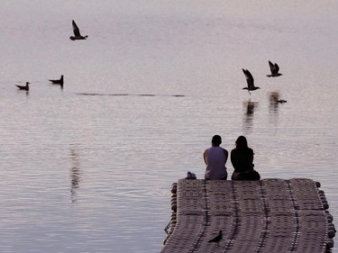 A couple watches the sun set on the docks of the Glenmore Sailing Club at 8601 24 St S.W. as they enjoy the end of the hot and sunny weekend.