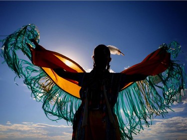 Faith Starlight  is silhouetted against the sun as she practices her fancy dance before competing at the Siksika Nation Fair Powwow.