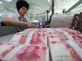 A teller counts yuan banknotes in a bank in Lianyungang, east China's Jiangsu province on August 11, 2015. China's central bank on August 11 devalued its yuan currency by nearly two percent against the US dollar, as authorities seek to push market reforms and bolster the world's second-largest economy. CHINA OUT