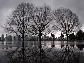 Cyclists ride through Stanley Park as rain falls in Vancouver, B.C.