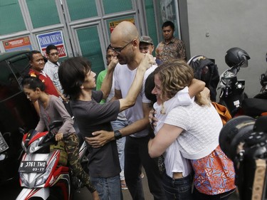 Canadian teacher Neil Bantleman, second right, hugs Indonesian teaching assistant Ferdinant Tjiong, left, as his wife Tracy Bantleman, right, hugs Sisca Tjiong after they were released from Cipinang prison in Jakarta, Indonesia, Friday, Aug. 14, 2015. A Canadian teacher and an Indonesian teaching assistant serving 10 years in an Indonesian prison for child sexual offenses were released Friday after a court overturned their convictions.