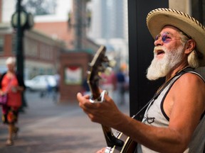 Andy Mitchell busks along Stephen Avenue in Calgary on Tuesday, Aug. 25, 2015. Mitchell, who has been busking since 1973, says he is undeterred by the smokey weather.