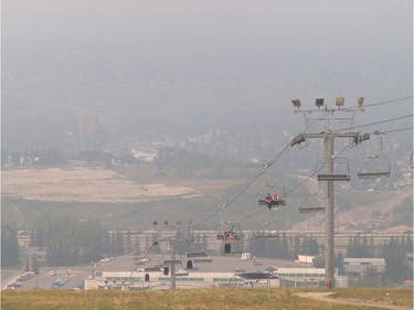 Chairlift riders rise above the settling smoke in the Bow River valley at WinSport in Calgary on Tuesday, Aug. 25, 2015.