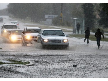Cars and pedestrians negotiate a flooded 19th street N.E. after a fast moving hail storm moved through Calgary on Tuesday afternoon.