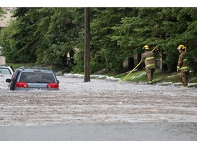 Firefighters check abandoned vehicles in flood waters along 5th avenue N.E. near 36th street after a powerful thunder and hail storm moved through the city on Tuesday afternoon.