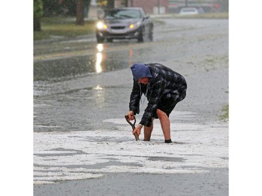 Mayland Heights resident Rick Nichol works to unplug storm sewers after a fast moving hail storm moved through Calgary Tuesday afternoon.