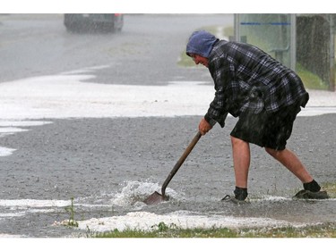 Mayland Heights resident Rick Nichol works to unplug storm sewers after a fast moving hail storm moved through Calgary Tuesday afternoon.