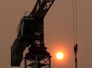 A construction crane in Bridgeland is silhouetted by the smoke shrouded sun at about 8:30 on Tuesday morning. The city is forecasted to be under heavy smoke warnings for at least another day.