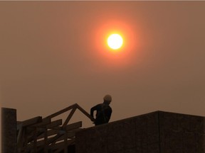 A construction worker in Bridgeland is silhouetted by the smoke shrouded sun at about 8:30 on Tuesday morning. The city is forecasted to be under heavy smoke warnings for at least another day.