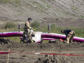 Firefighters remove fuel from a small plane that crashed and landed on its roof in the Walden community in southeast Calgary on Saturday, Aug. 22, 2015.