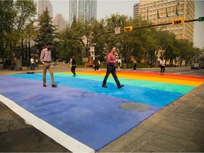 Pedestrians cross the city's first rainbow crosswalk, painted in advance of the 25th annual Calgary Pride Festival, at City Hall.