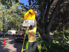 Crews from the City of Calgary switch a school zone sign to a playground zone sign near F.E. Osborne Junior High School in the northwest neighbourhood of varisty on Aug. 20, 2015.