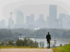 Charlie Coffin walks along the pathway above Max Bell Centre with the smoke shrouded downtown in the distance in Calgary Monday August 24, 2015.