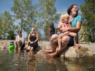 Bobbi Sampson, right, reacts to being splashed at the Bow River wadding pool at St. Patrick's Island in Calgary on Monday, Aug. 10, 2015.