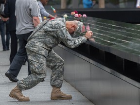 U.S. army Sgt. Edwin Morales prays during a ceremony at the World Trade Center site in New York on Friday, Sept. 11, 2015. First responders finally get their financial due, notes columnist Chris Nelson.