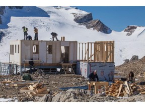 Crews work on the second story of the hut with the des Poilus Glacier in the background.