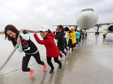Sarah Foreman, left, and the rest of her Team United Way, pull a 200,000 lb Airbus A300 during the fourth annual Plane Pull event put on by United Way Calgary and Area at UPS in Calgary on September 13, 2015.