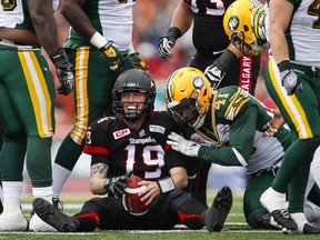 Calgary Stampeders' quarterback Bo Levi Mitchell, centre, reacts to being sacked by Edmonton Eskimos' Odell Willis during first half CFL football action in Calgary on Monday, September 7, 2015.