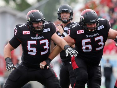 Calgary quarterback Bo Levi Mitchell is well covered by offensive linemen Brad Erdos, 53, and Pierre Lavertu, 63 as the Calgary Stampeders played host to the Edmonton Eskimos for the Labour Day Classic on September 7, 2015 at McMahon Stadium.