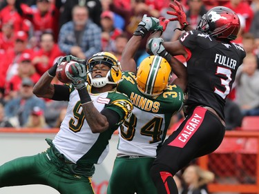 Edmonton Eskimos Patrick Watkins, left and Ryan Hinds intercept this pass for wide receiver Jeff Fuller during the first half if the Labour Day Classic action at McMahon Stadium on Monday September 7, 2015.