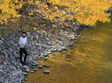 Fall colours reflect in the Bow River as Clint Atayiu tries his luck fishing along the Bow River on Sunday September 20, 2015.