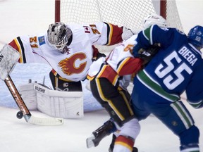 Calgary Flames defenseman Kenney Morrison (53) tries to clear Vancouver Canucks defenseman Alex Biega (55) from getting a shot on Calgary Flames goalie Karri Ramo (31) during second period pre-season NHL action Vancouver on Saturday. The battle for control of Calgary's crease continues with Ramo, Jonas Hiller and Joni Ortio in camp.